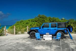 a blue jeep parked on the beach with two chairs at Ocean Dream Studio Blue - Ocean View in Long Bay Hills +5 photos
