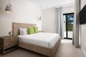 a bedroom with a white bed with green pillows at Upper East Side Enclave # 18 in Leeward +28 photos
