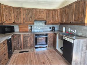 a kitchen with wooden cabinets and a black refrigerator at Cabin and Guest house in Haugesund