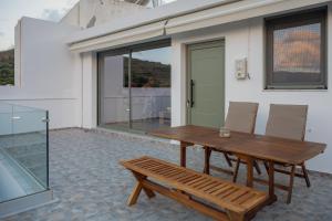 a wooden table and a bench on a patio at Cretan View - Valley & Mountains View Sitia in Áyios Yeóryios