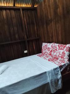 a bed with a red and white pillow on it at Miranda in Arroyo Chico Arriba