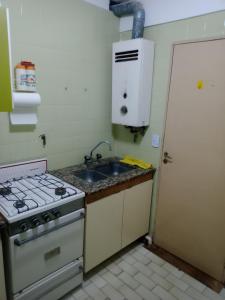 a kitchen with a stove and a sink at Arco Iris in Miramar +2 photos