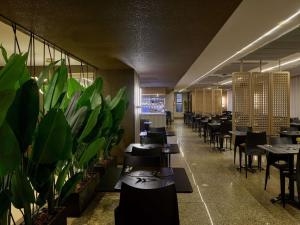 a restaurant with tables and chairs and potted plants at Mercure Belo Horizonte Lourdes in Belo Horizonte