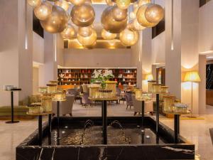 a lobby with tables and chairs and gold chandeliers at Sofitel Marrakech Palais Impérial & Spa in Marrakesh