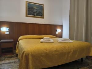 a bedroom with a yellow bed with towels on it at Domus Cesena in Cesena