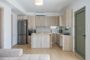 a kitchen with wooden cabinets and a refrigerator at Cretan View - Valley & Mountains View Sitia in Áyios Yeóryios