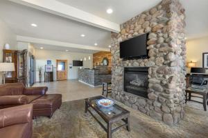 a living room with a stone fireplace with a flat screen tv at Best Western Swiss Clock Inn in Pecos