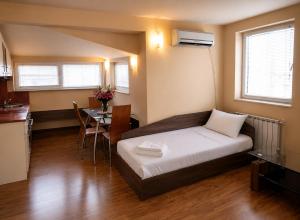 a bedroom with a bed and a table and a kitchen at Hotel Maria in Vratsa
