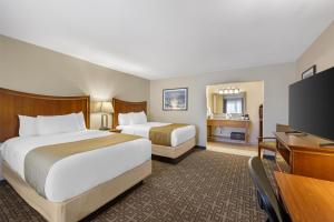 a hotel room with two beds and a flat screen tv at Best Western Swiss Clock Inn in Pecos +53 photos