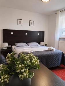 ein Schlafzimmer mit einem Bett und einem Tisch mit Blumen in der Unterkunft AGAT Karpacz in Karpacz