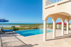 a swimming pool with a patio and an umbrella at Breathtaking Chalk Sound Private Pool Sunset Villa in Providenciales