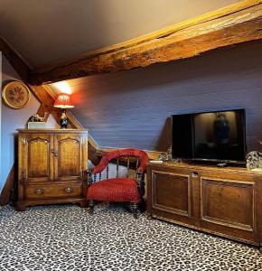 a living room with a tv and a red chair at St Columbas Boutique BnB in Weobley