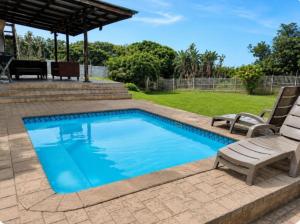 a swimming pool with two chairs and a table at Serenity Six Beach House in Hibberdene