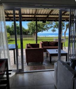 a screened in patio with couches and a table at Serenity Six Beach House in Hibberdene