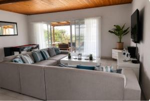 a living room with a couch and a table at Serenity Six Beach House in Hibberdene