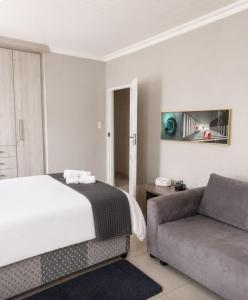 a bedroom with a bed and a couch at Serenity Six Beach House in Hibberdene +18 photos