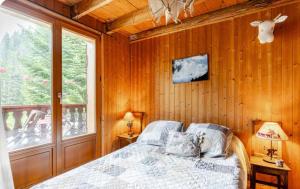 a bedroom with wooden walls and a bed and a window at Chambre 2 balcon in Mont-Saxonnex