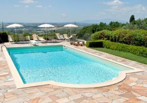 una piscina en un patio con sillas y sombrillas en Villa Da Vinci, en Vinci