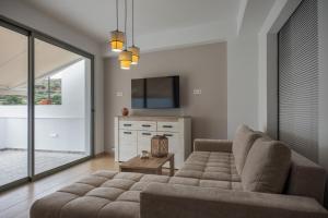 a living room with a couch and a tv at Cretan View - Valley & Mountains View Sitia in Áyios Yeóryios