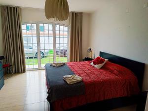 a bedroom with a bed with a red blanket and a window at Oasis Rest in Porto Martins