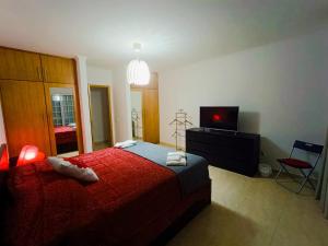 a bedroom with a red bed and a television at Oasis Rest in Porto Martins