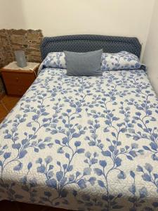 a bed with a blue and white comforter with a pillow at Pensión Atlántico in Muxia