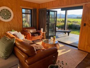 a living room with a leather couch and a table at Fiery Peak Eco-Retreat with Stargazing & Hot tub in Geraldine +43 photos
