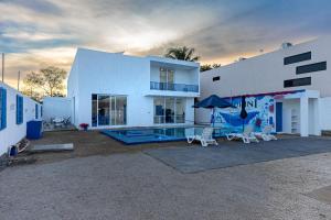 a white house with a pool and chairs and an umbrella at Santorini Resort in Mérida