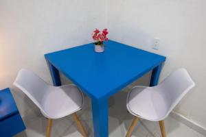 a blue table with two white chairs and a vase with flowers at Santorini Resort in Mérida