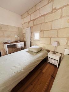 a bedroom with two beds and a brick wall at Le Clos de Tuffeau in Turquant