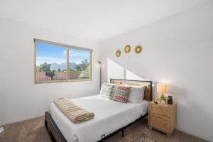 a white bedroom with a bed and a window at Sunny & Bright Charm with Community Pool in Tucson