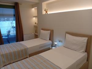 two beds in a hotel room with a window at Fyki sea view apartment in Vlikhón