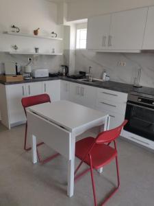 a kitchen with a white table and red chairs at Fyki sea view apartment in Vlikhón