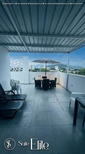 a patio with a table and chairs and an umbrella at Suites Privadas - Elite Valledupar, Cerca CC Guatapurí y Rio Guatapurí in Valledupar