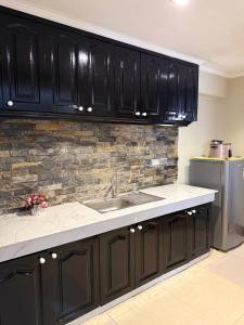 a kitchen with black cabinets and a sink at Serenity Home - 4 bedroom home in Iloilo City