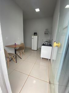 a white kitchen with a table and a stove at Aconchegante é silencioso in Rio Verde