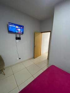 a room with a tv on the wall and a door at Aconchegante é silencioso in Rio Verde