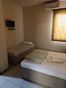a room with two beds and a tv and a window at Ubaense Suites in Ubá +6 photos
