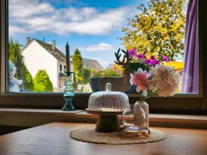 a table with a vase of flowers and a window at Ferienwohnung Dreamy Daisy in Morbach +9 photos