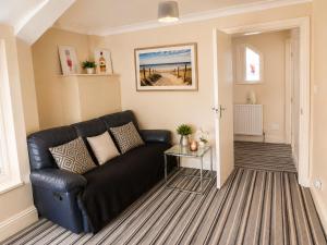 a living room with a black couch and a table at Amethyst Loft Room in Farnham Royal