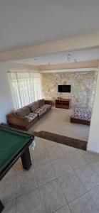 a living room with a pool table and a stone wall at Pousada Peruibe in Peruíbe