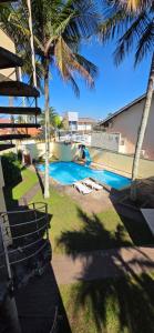 a swimming pool with a boat in a yard with palm trees at Pousada Peruibe in Peruíbe