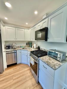 a kitchen with white cabinets and a stove top oven at The Happy Hive in Bridgton