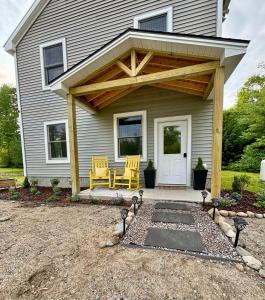 a porch with awning and chairs on a house at The Happy Hive in Bridgton