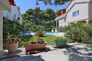 a garden with potted plants and a house at Family-friendly apartments with swimming pool Banjol, Rab - 5007 in Rab