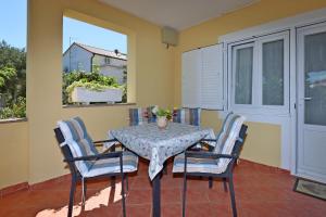 a table and chairs on a balcony with a table at Family-friendly apartments with swimming pool Banjol, Rab - 5007 in Rab