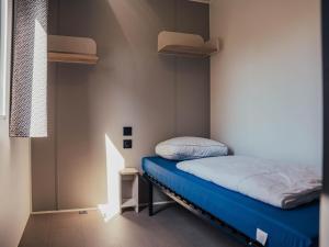 a small bedroom with a bed with a blue mattress at Timber-Lodge in Vessem +21 photos