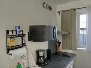 Eine Küche mit Arbeitsplatte und einem Fernseher an der Wand in der Unterkunft studio, in Doue