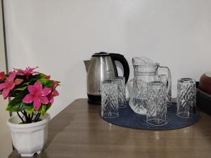 a table with glasses and a pitcher and a vase with flowers at Colman Apart Central 07 in Ciudad del Este