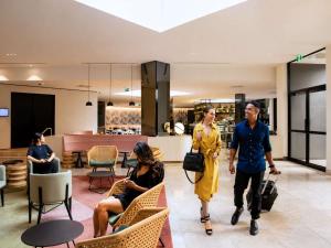 a group of people walking through a shopping mall at Novotel Sydney International Airport in Sydney